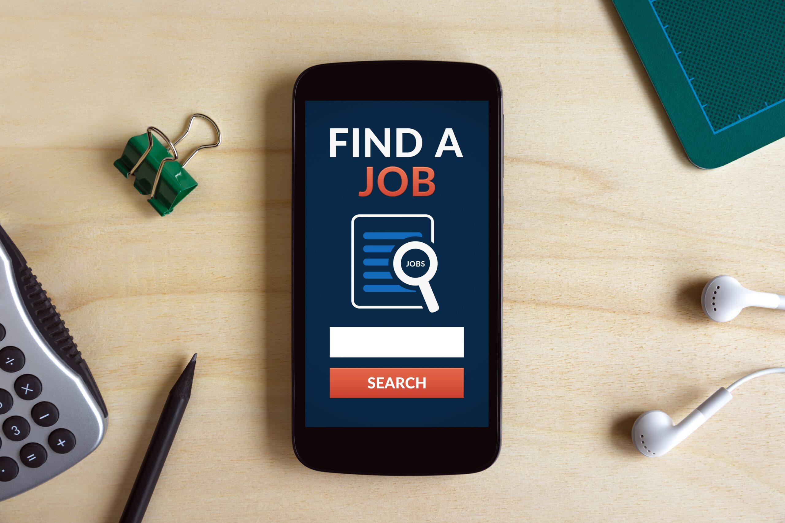 Find a Job Phone scaled A smartphone is on a table with its screen on a "find a job" website.
