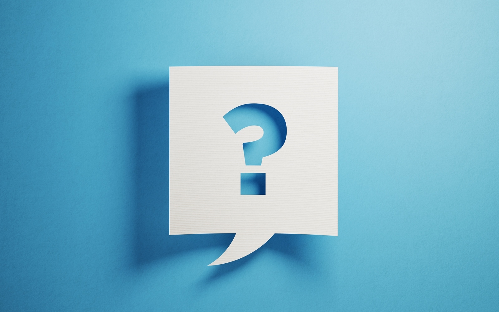 Question Mark A post it note has a cutout question mark shape. The post it note is white while the background is blue.