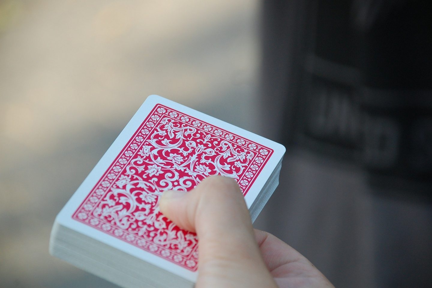 A close-up view of a hand holding a deck of cards with the back of the card's design facing the viewer.