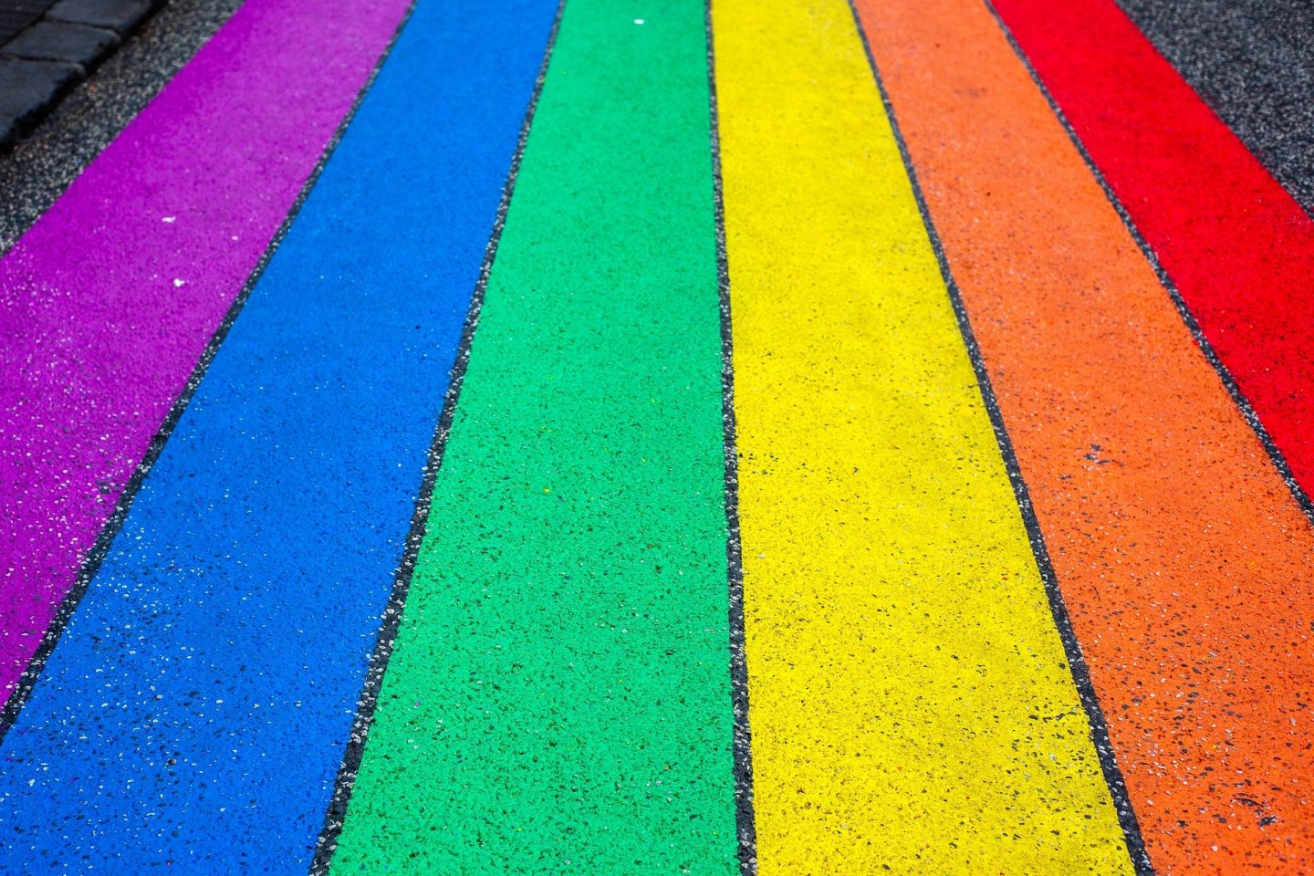 Pride colors are shown with chalk lines on a road. The colors used are from left to right showing: purple, blue, green, yellow, orange, and red.