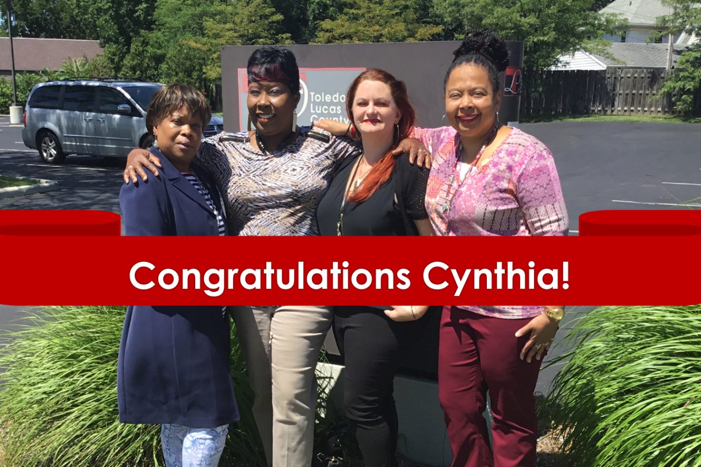 A view of Toledo Lucas County Public Library staff at South Branch. The text on the image reads "Congrats Cynthia!" on a red illustration of a banner.