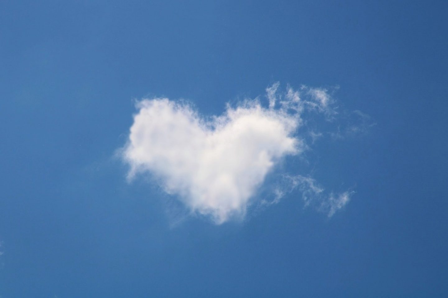 A blue sky with a white cloud in the shape of a heart.