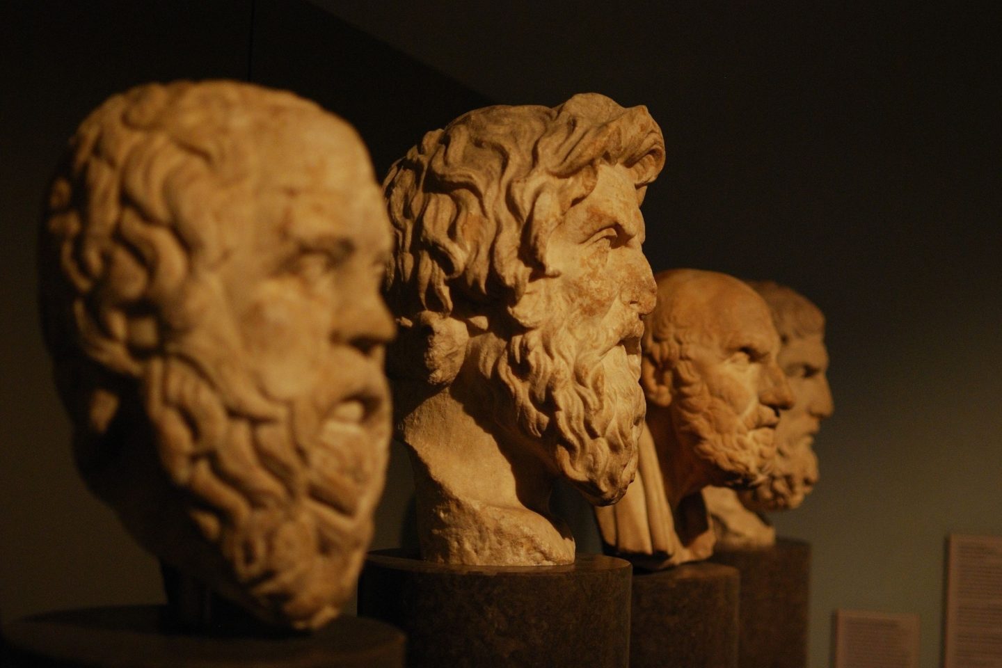 Side view of marble sculptures of Greek philosophers. From left to right, the heads pictured include Sokrates, Antisthenes, Chrysippos, and Epikouros.