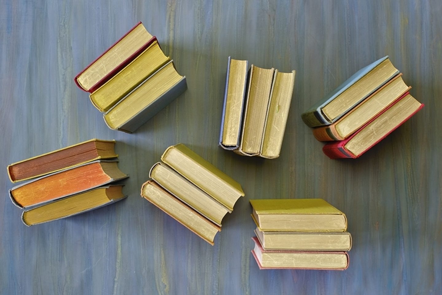 Six groups of three books standing up on a floor.