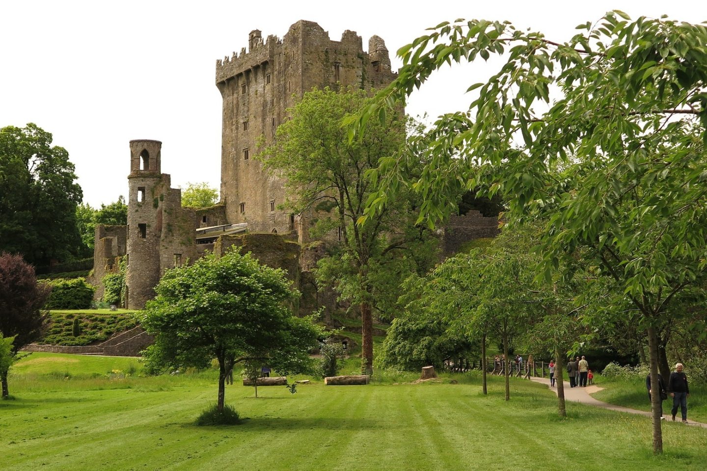 A distant view of people walking towards Ireland's Blarney Castle and Gardens.