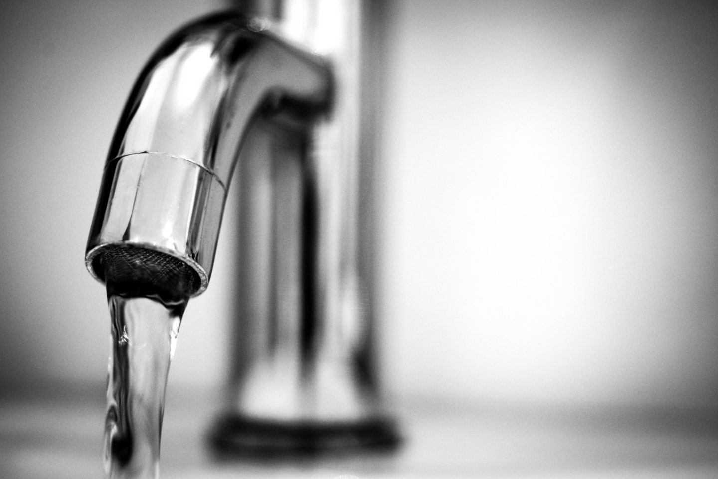 A close-up view of a silver faucet with water running out of its opening.