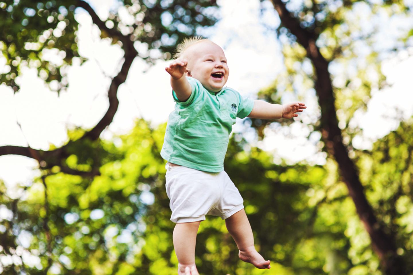 A toddler is seen laughing while being thrown up in the air.