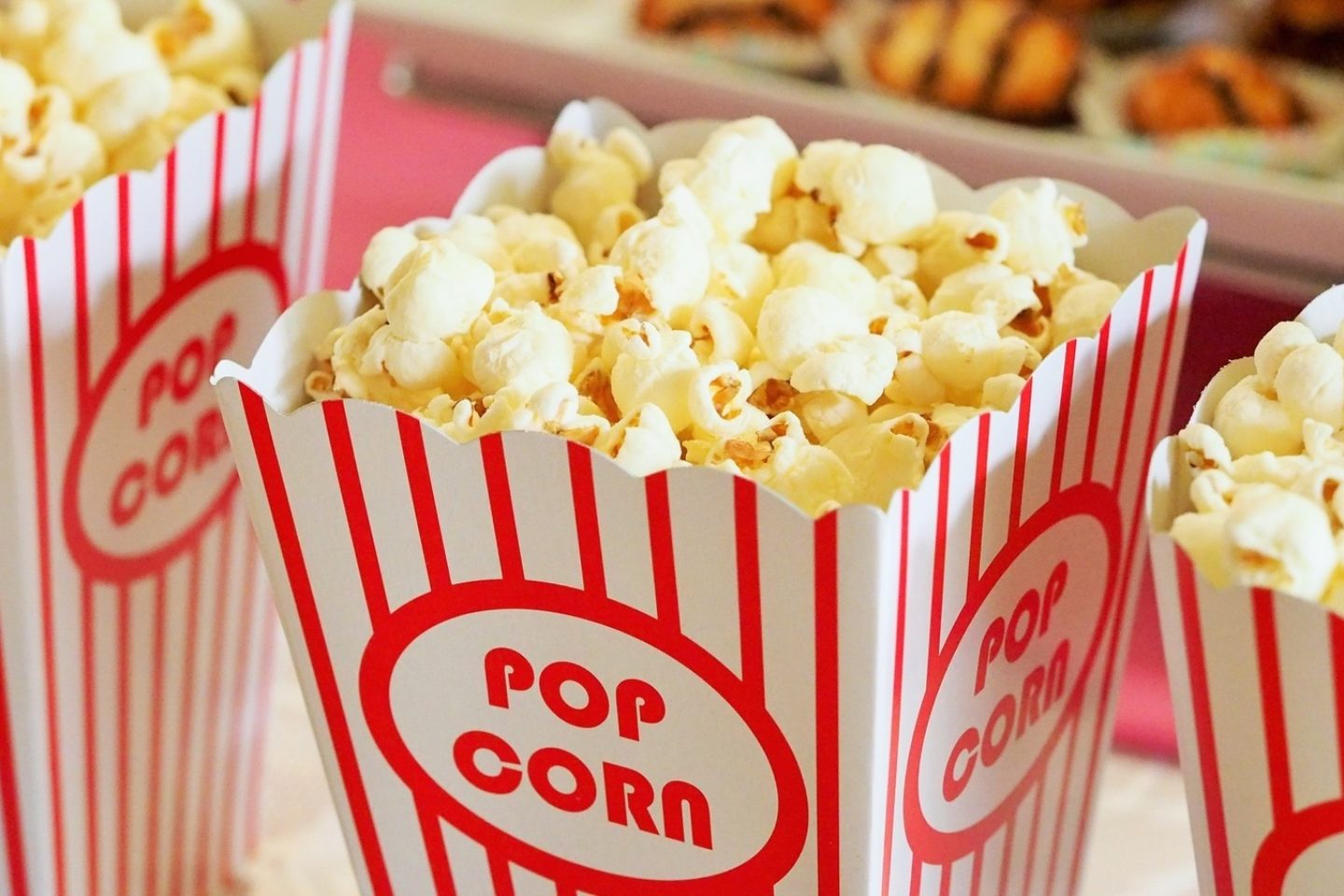 A close-up view of the top of three movie theatre popcorn tubs with popcorn inside.