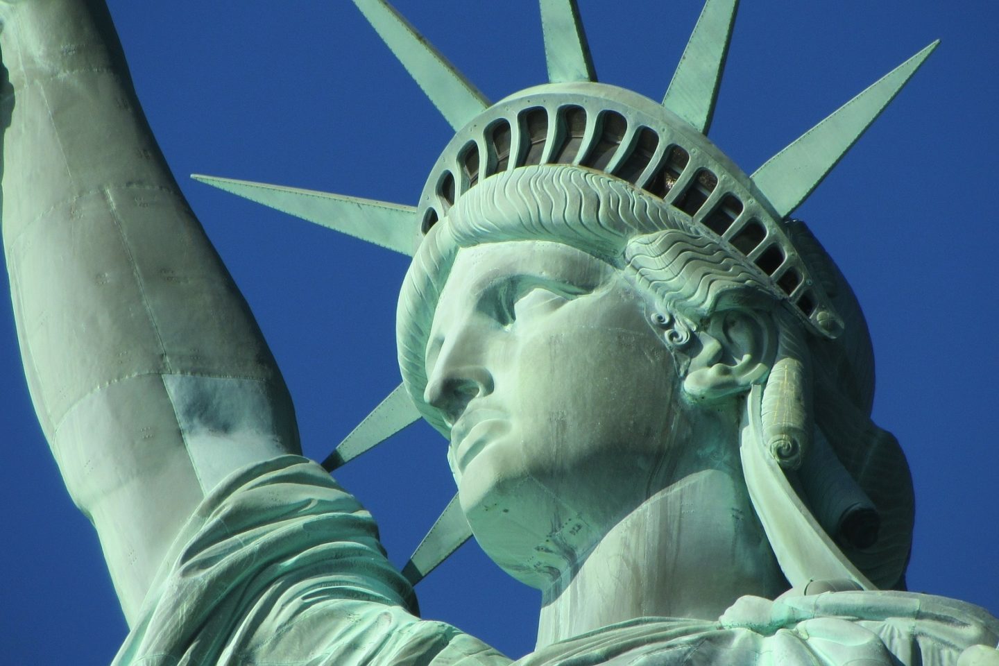 Close-up view of the Statue of Liberty by her face and raised arm.