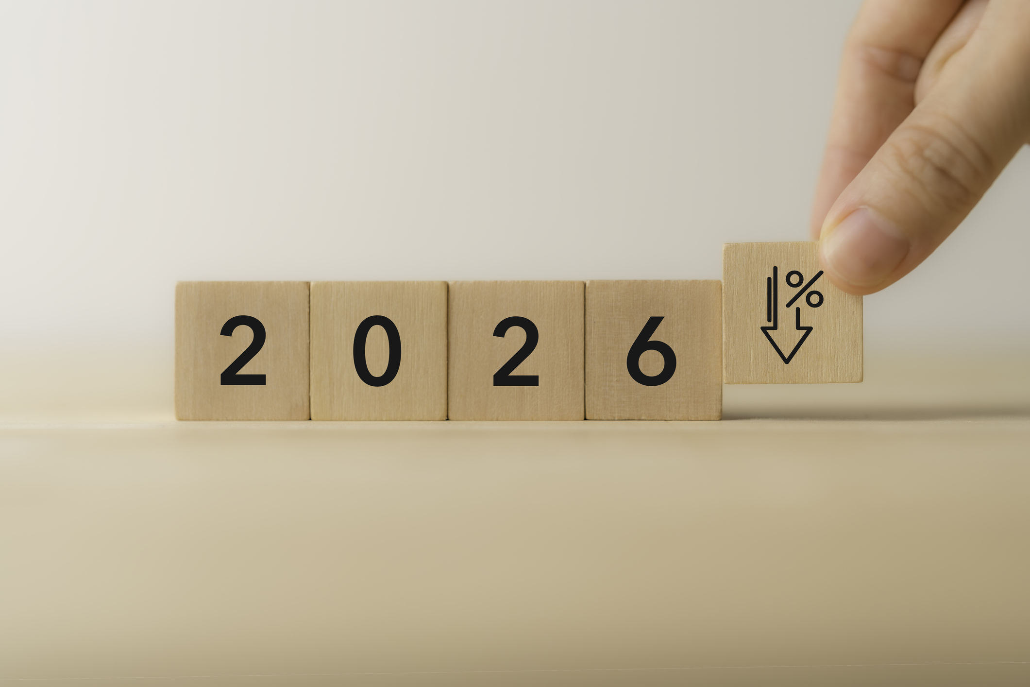 2026 Economic Decline Concept. Wooden blocks displaying “2026,” with hand placing a final block with downward arrow and percentage symbol. Economic decline,financial downturns, and market challenges.