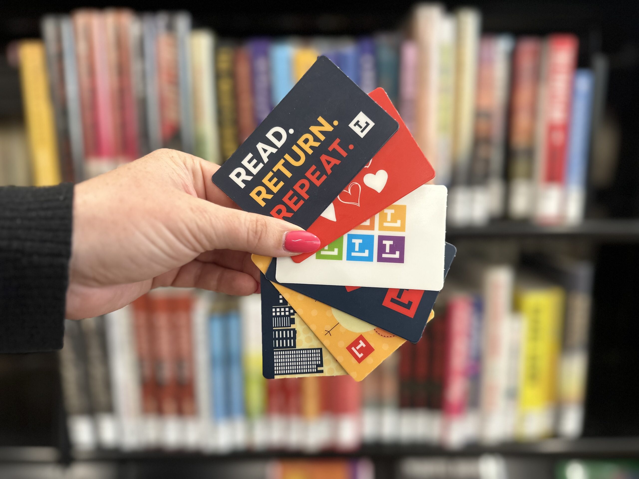 Library Cards2 A woman's hand holds six library cards. They are spread out to show the different design options for a library card at the Toledo Lucas County Public Library.