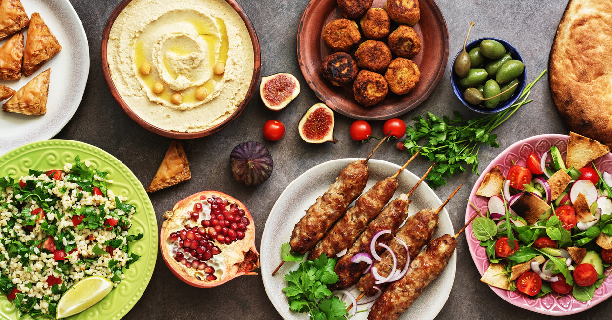 Hummus, tabbouleh salad, Fattoush salad, pita, meat kebab, falafel, baklava, and pomegranate.