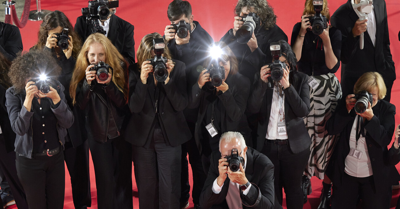 Crowd of paparazzi taking photos at a red carpet event.