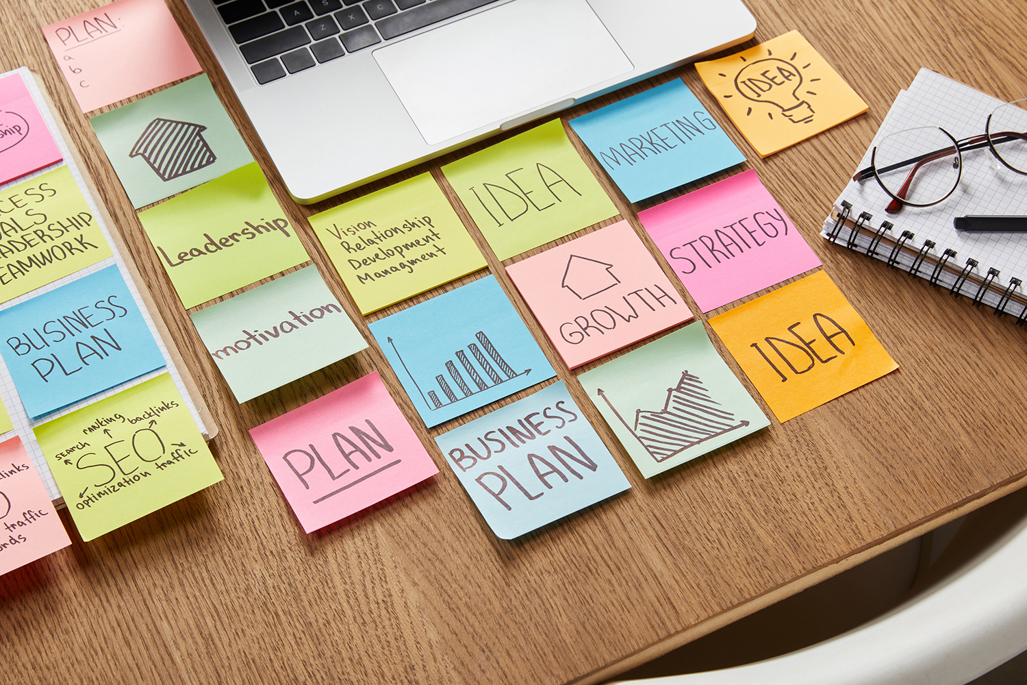 high angle view of paper stickers with business strategy and laptop on tabletop small business and nonprofit support brochures