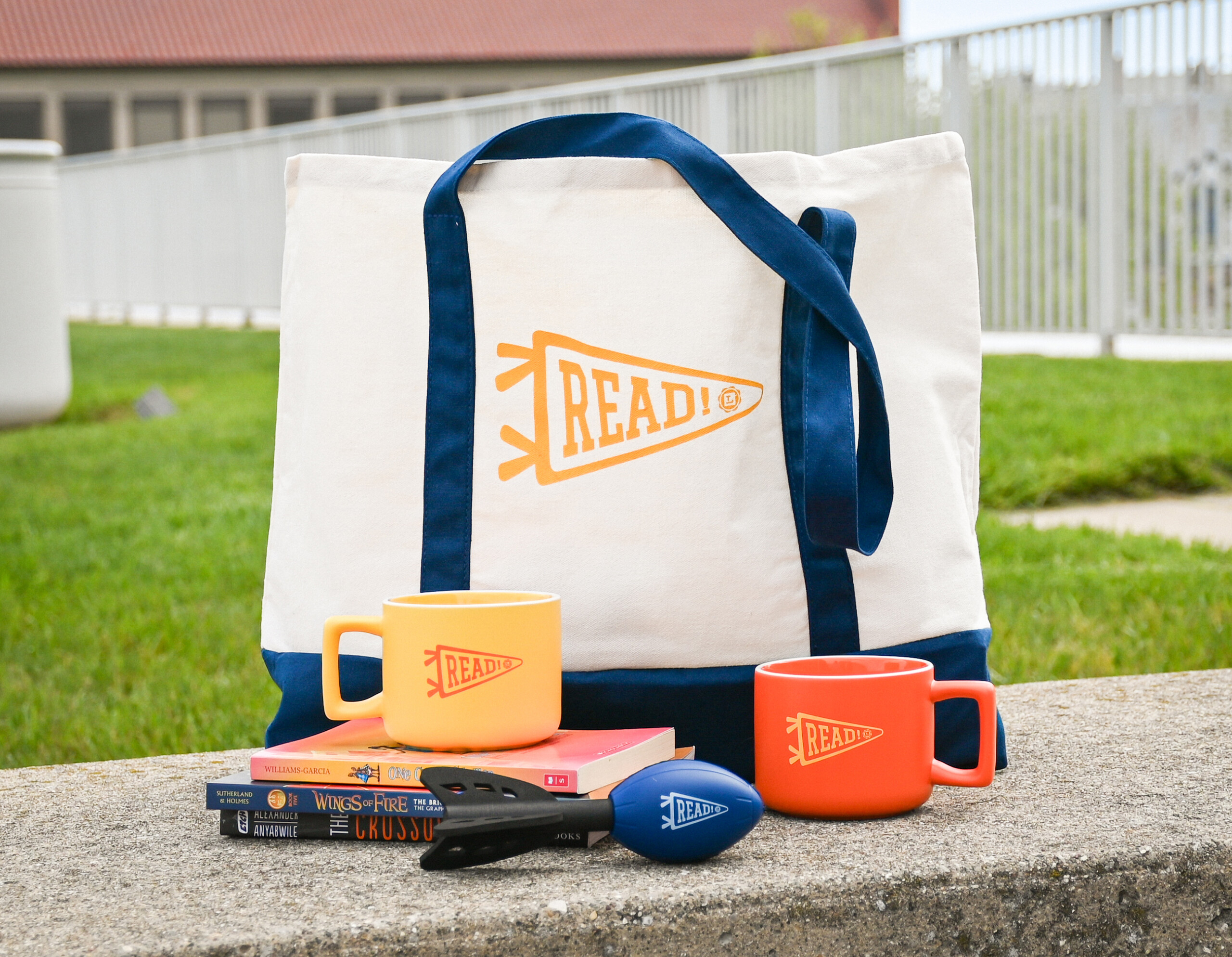 Photo of Summer Read prizes, which are a tote bag, mugs, a football flinger, and books. Photo of Summer Read prizes, which are a tote bag, mugs, a football flinger, and books.