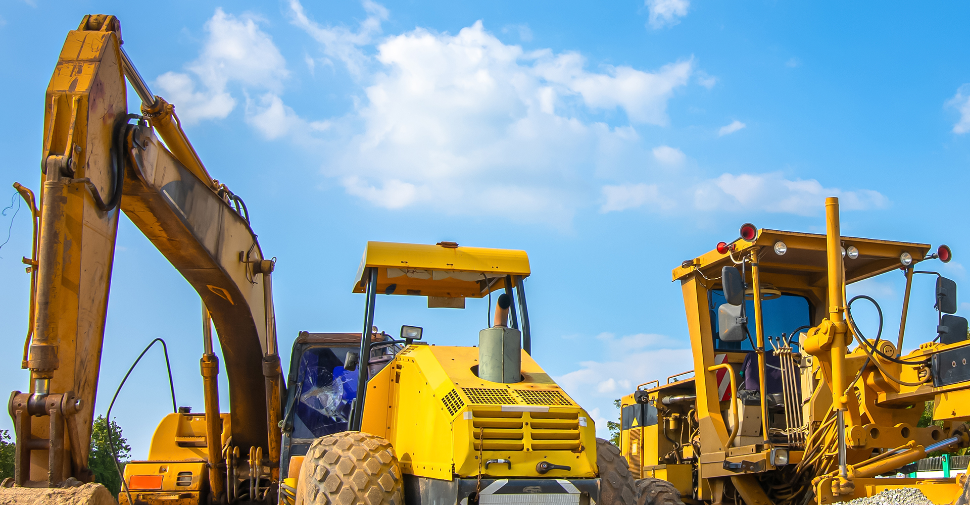 Backhoe, grader and road roller on the ground at site construction.